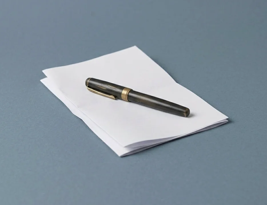 A fountain pen resting on a stack of clean paper